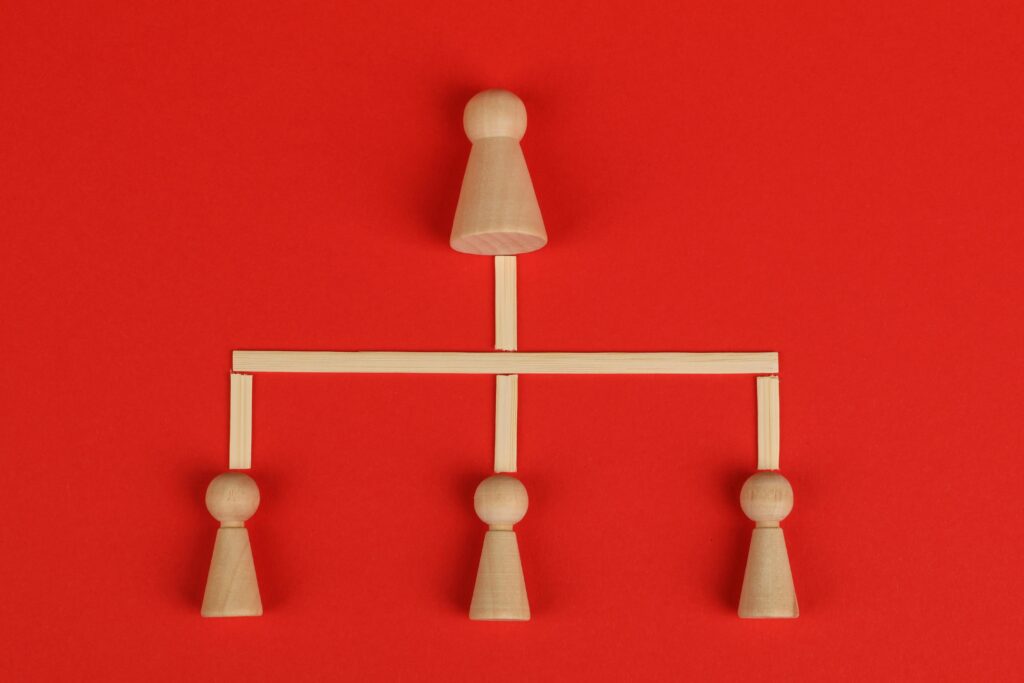 Conceptual depiction of hierarchy using wooden pieces on a vibrant red background.